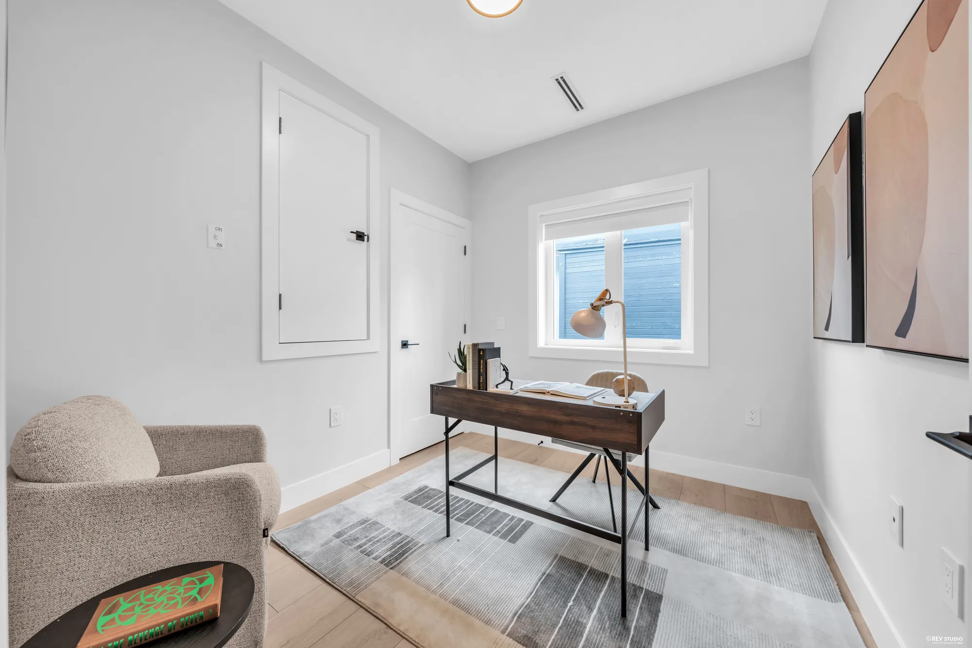 The third bedroom photographed as an office: a desk under the window, an armchair, a closet door