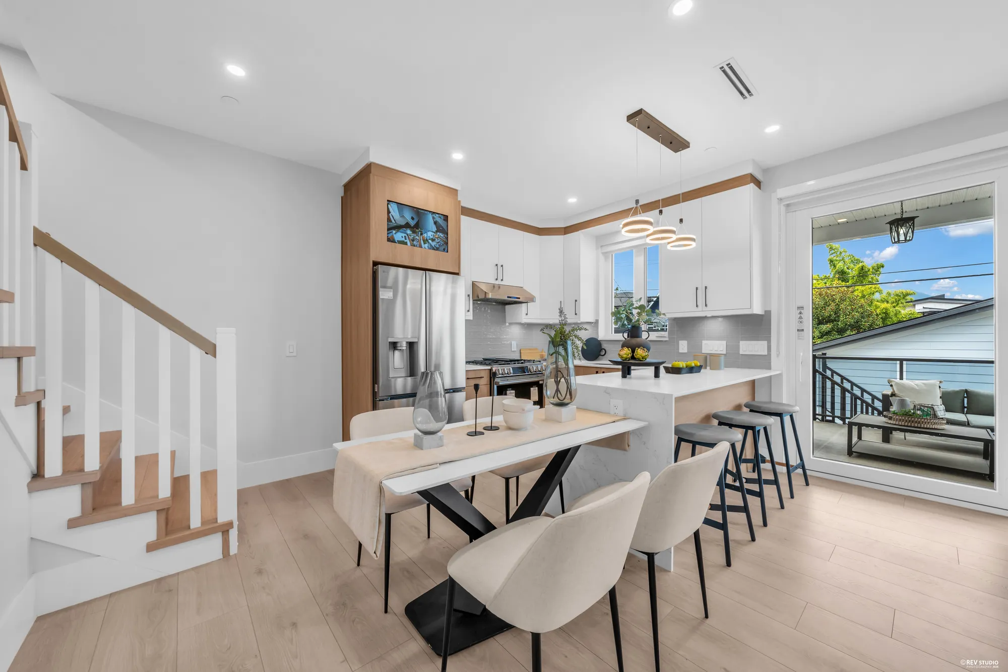 The dining area at the foot of the stair: a table and four chairs, the kitchen behind, the balcony doors to the right