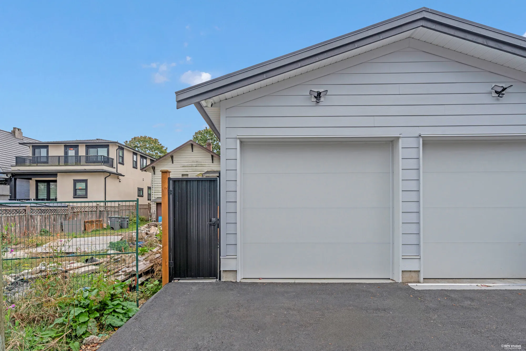 The garage from the lane: a white sectional door, a side door, the black fence beside it