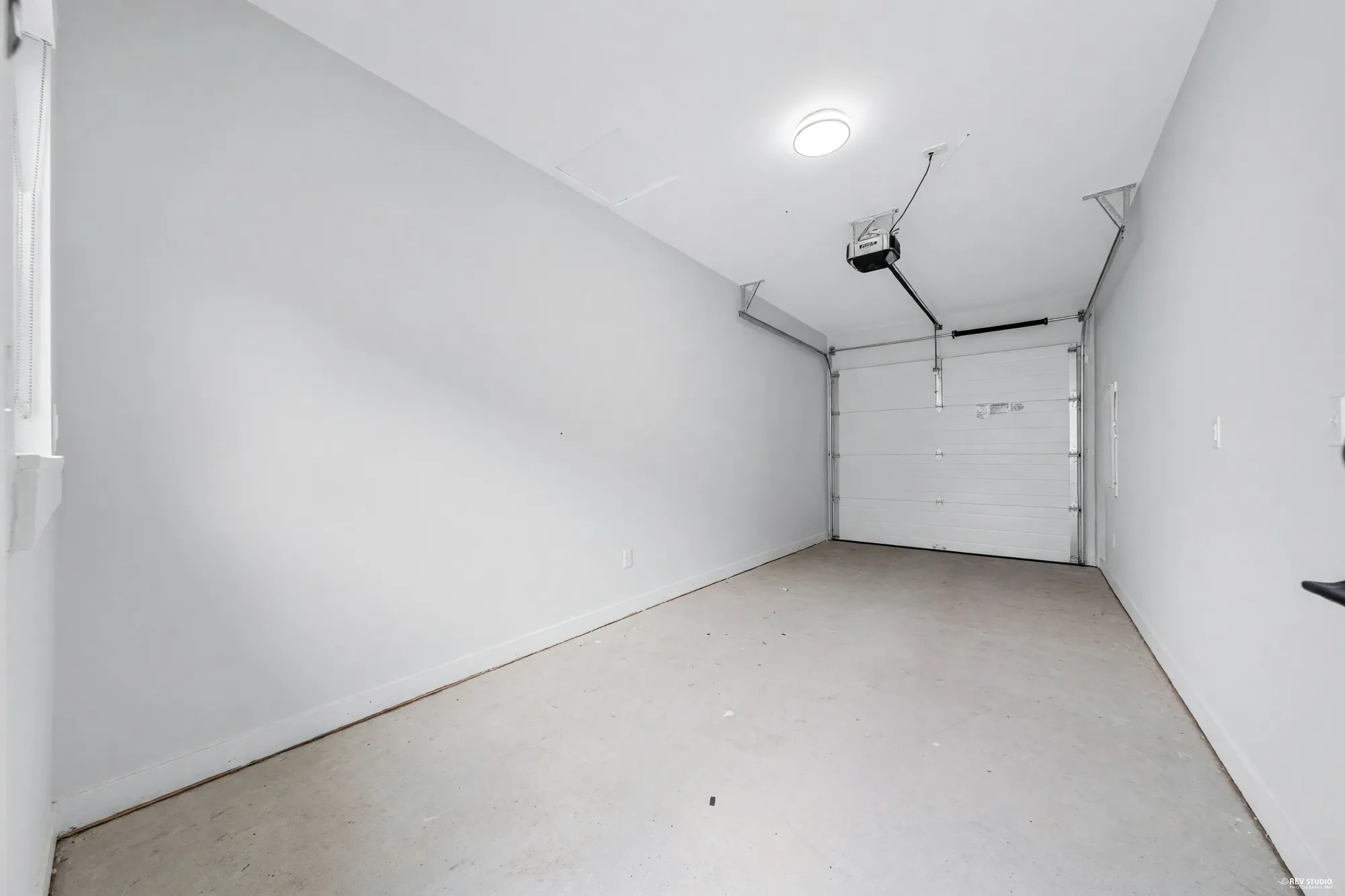 Inside the garage: bare walls, the sectional door and its opener, an empty concrete floor