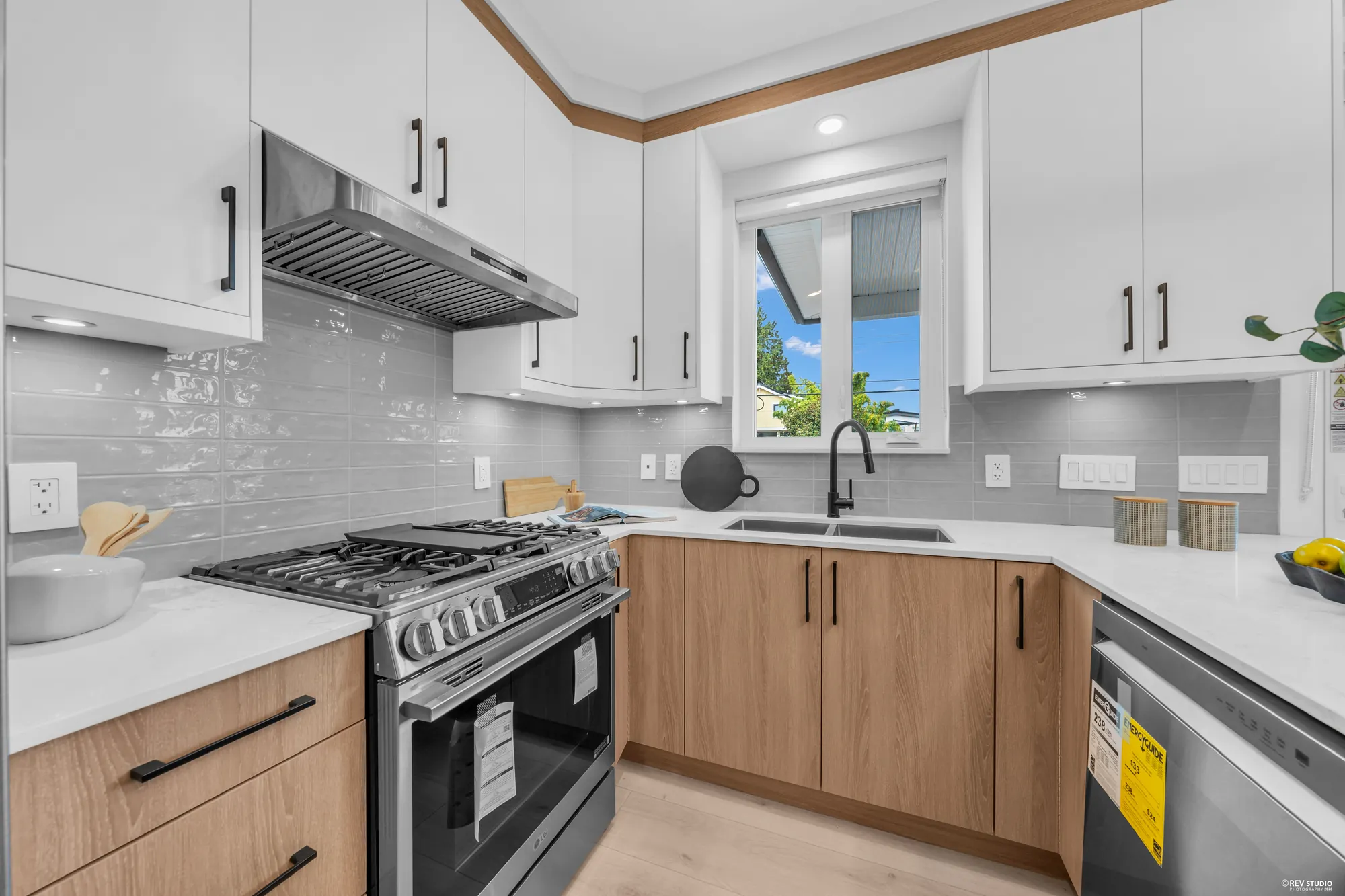 The gas range and hood, the tiled backsplash, the sink and dishwasher