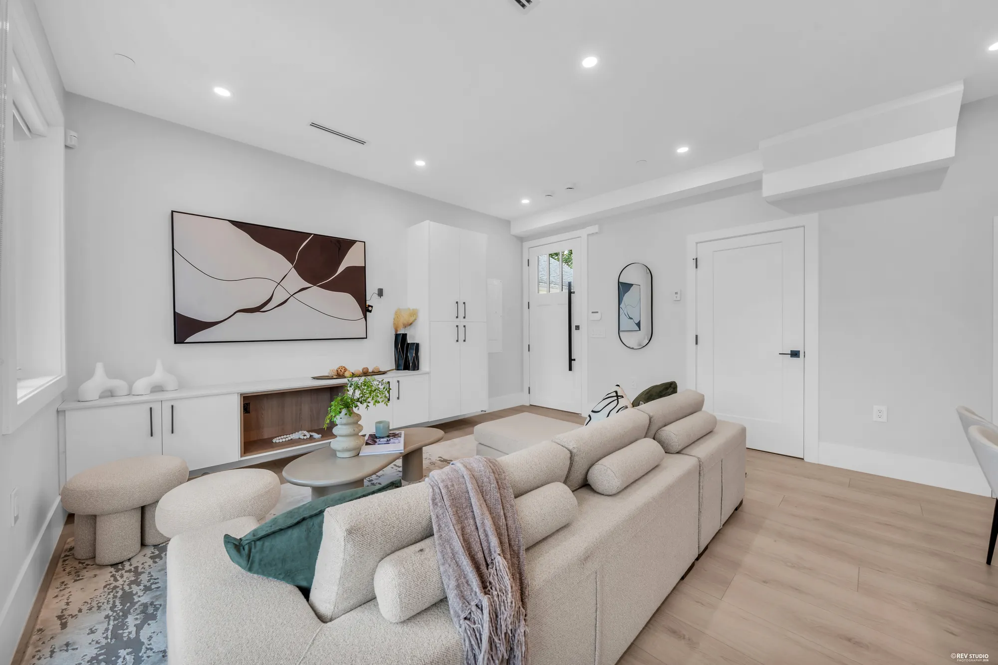 The living room toward the entry door and an oval mirror, the sectional and a round coffee table