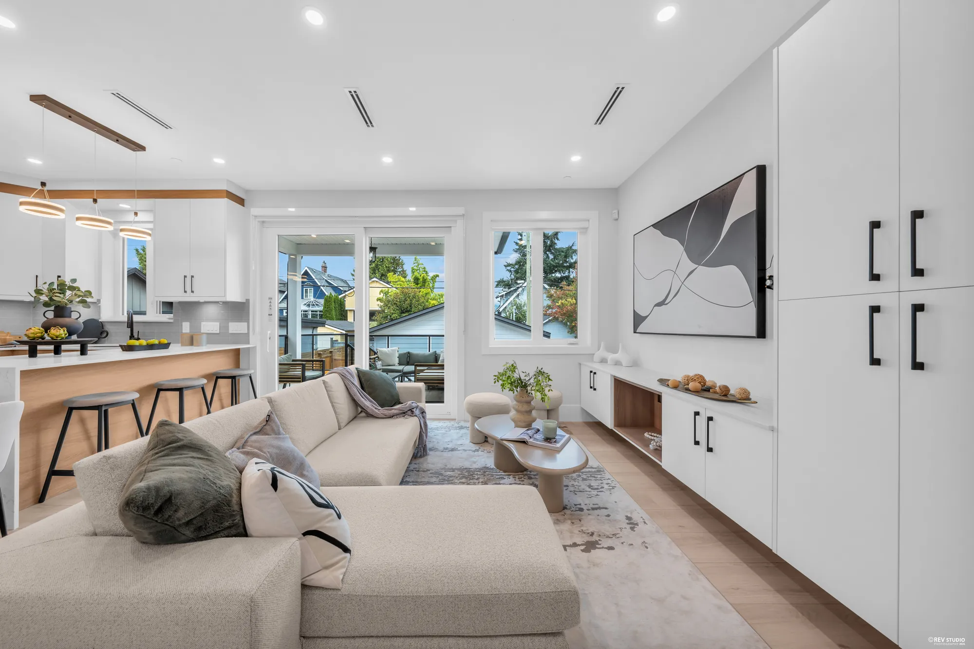 Along the wall of white built-ins toward the balcony doors, the kitchen on the left