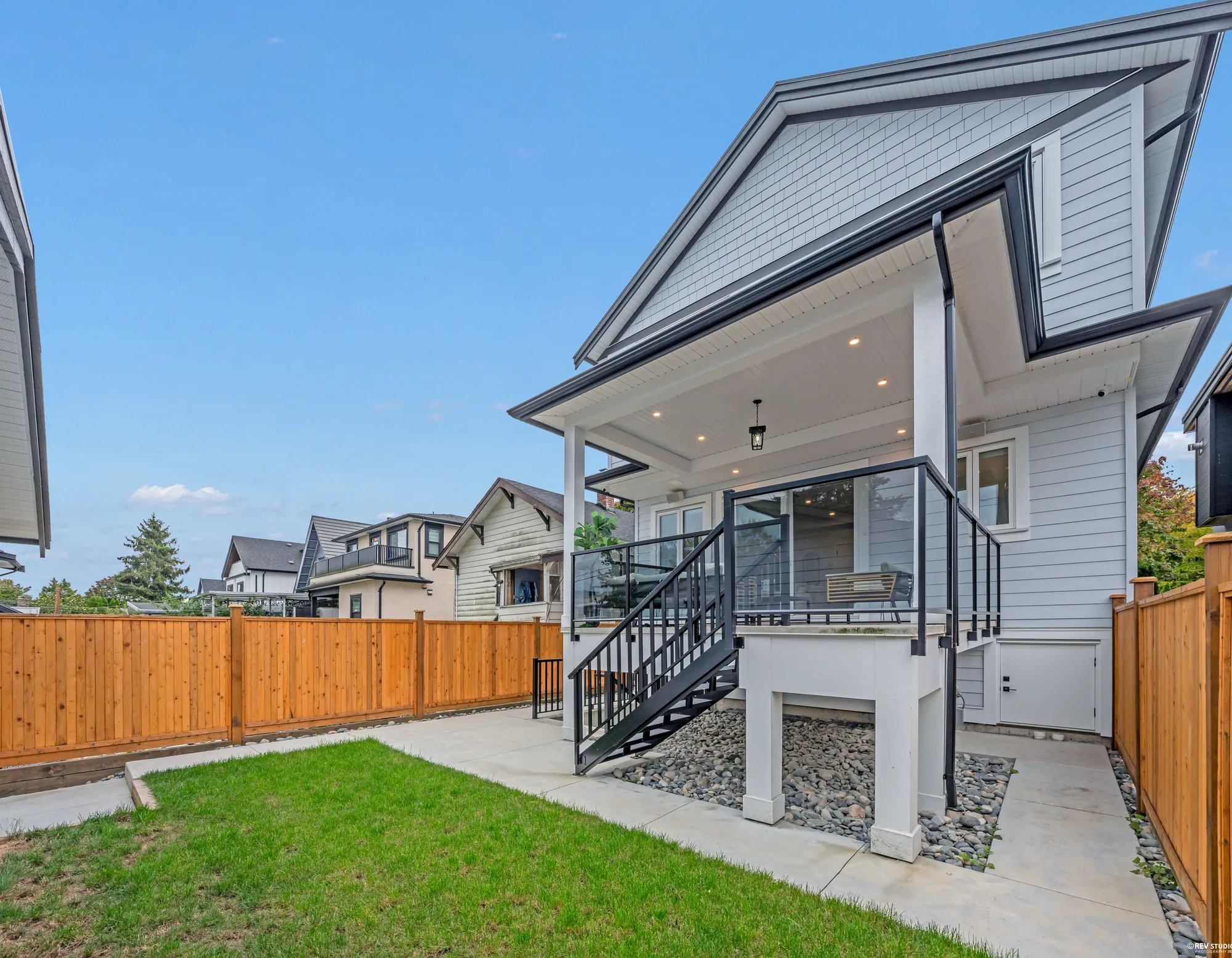 The back and the yard from the other side, the balcony stair coming down to the path, the new fence around the turf