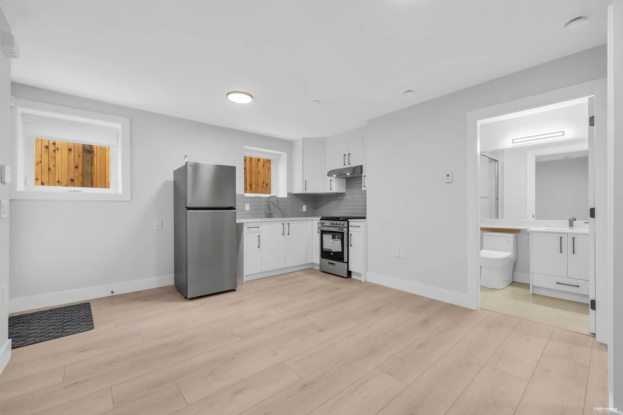 The lower kitchen with the fridge and the open bathroom door beside it