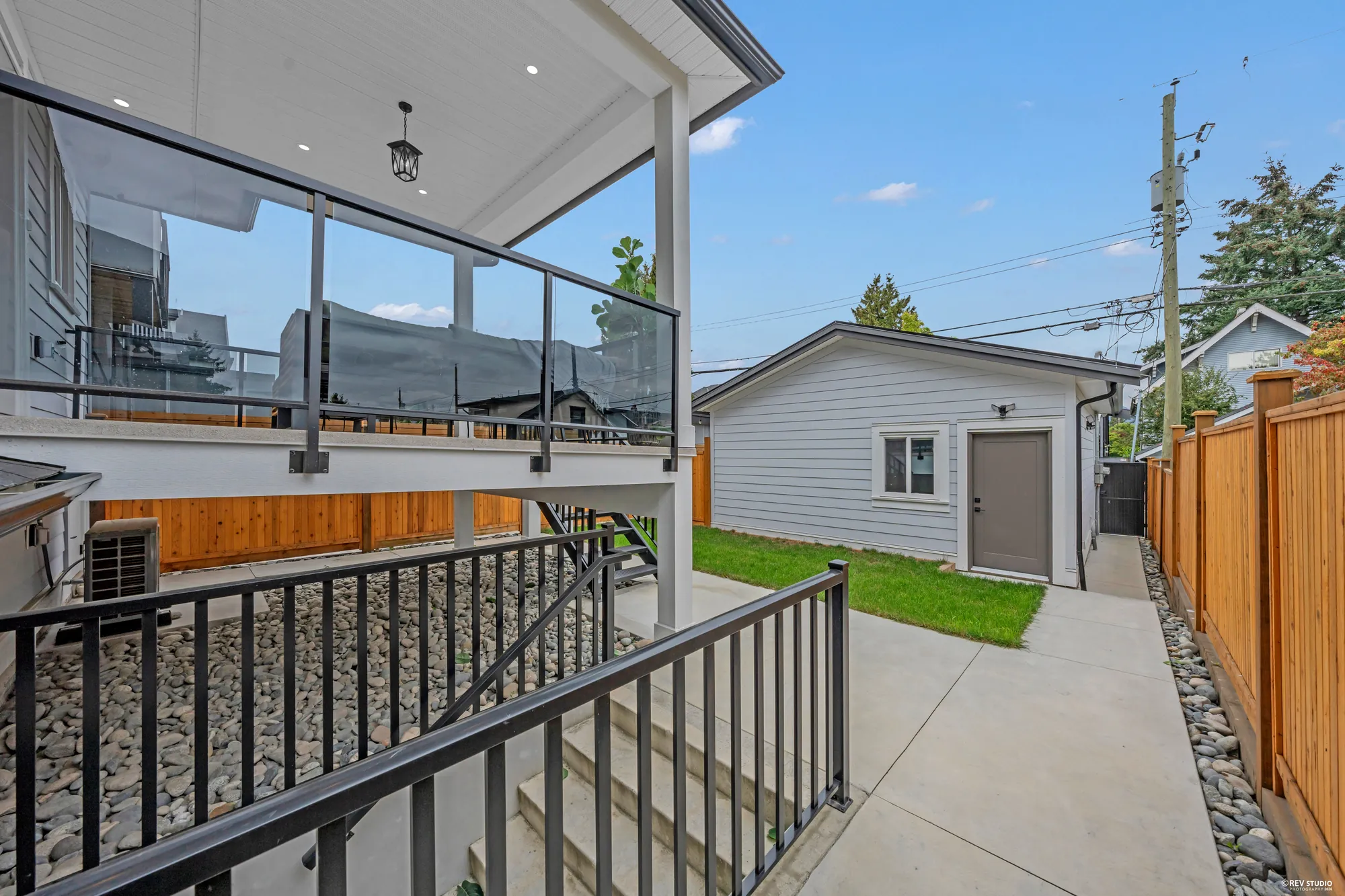 From the balcony: the stair down to the path, the turf, and the garage at the lane